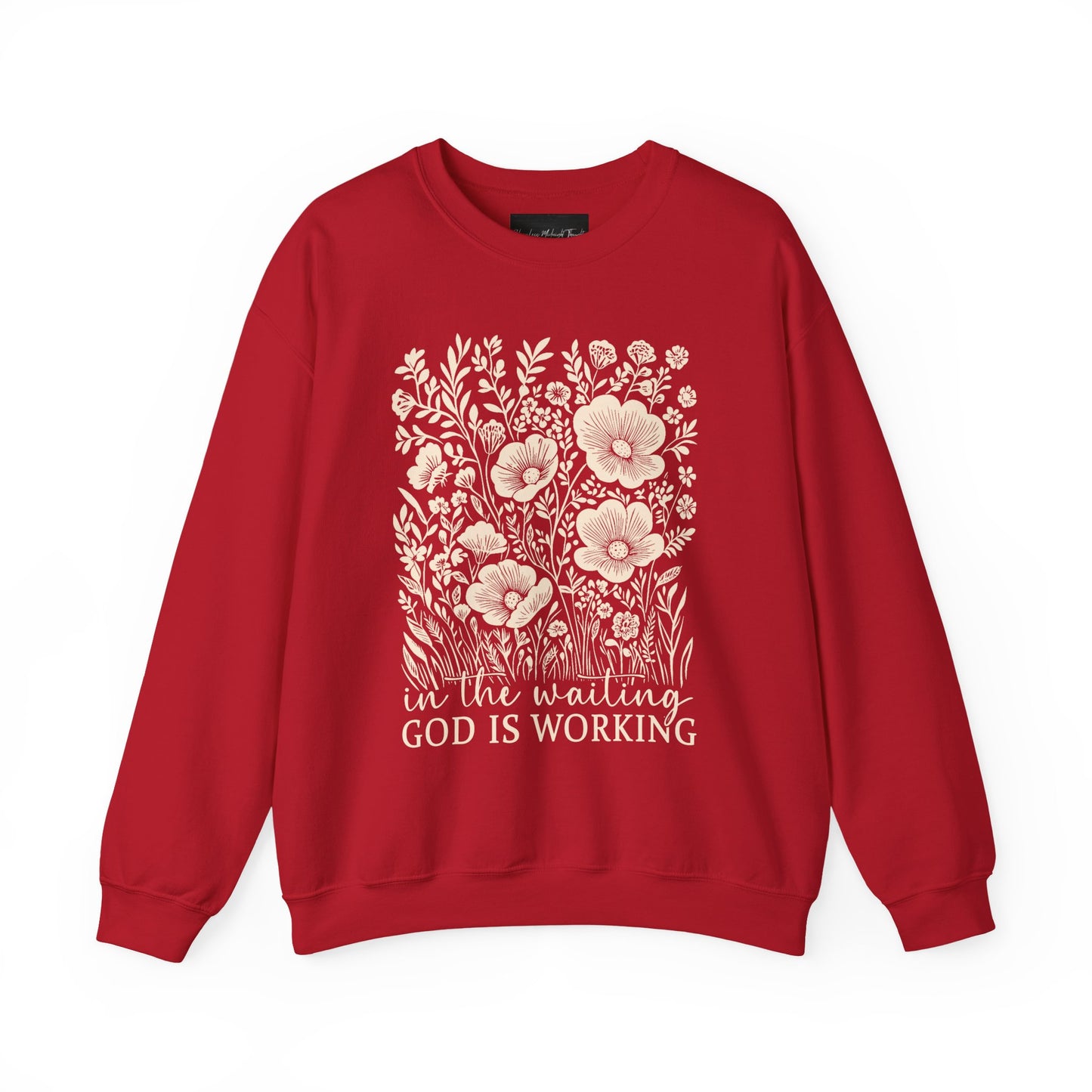 On the front of this custom women's Christian pullover sweatshirt are a bunch of wildflowers with the words in the waiting God is working underneath the flowers.