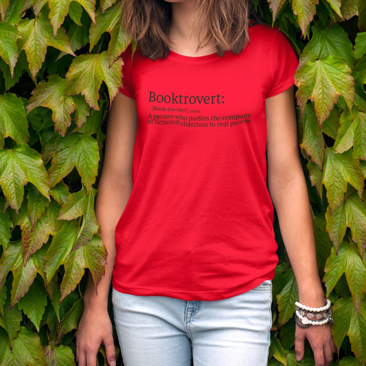 On the front of this custom youth t-shirt it says the word Booktrovert in large letter with the meaning of the words underneath it, on the back of the shirt is an image of a large stack of books.