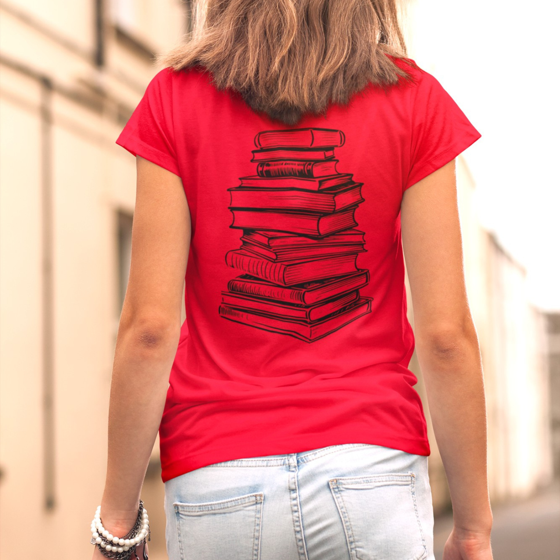 On the front of this custom youth t-shirt it says the word Booktrovert in large letter with the meaning of the words underneath it, on the back of the shirt is an image of a large stack of books.