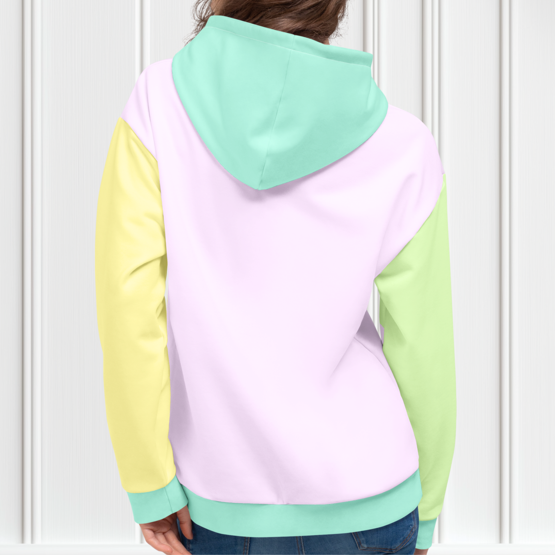 A custom hand sewn unisex hoodie that has a pastel color block design, the front and the back of the sweater are a light purple with the bottom waistband, the front pocket, hood and each cuff is a light mint green, the left sleeve is yellow and the right sleeve is a light grass green.