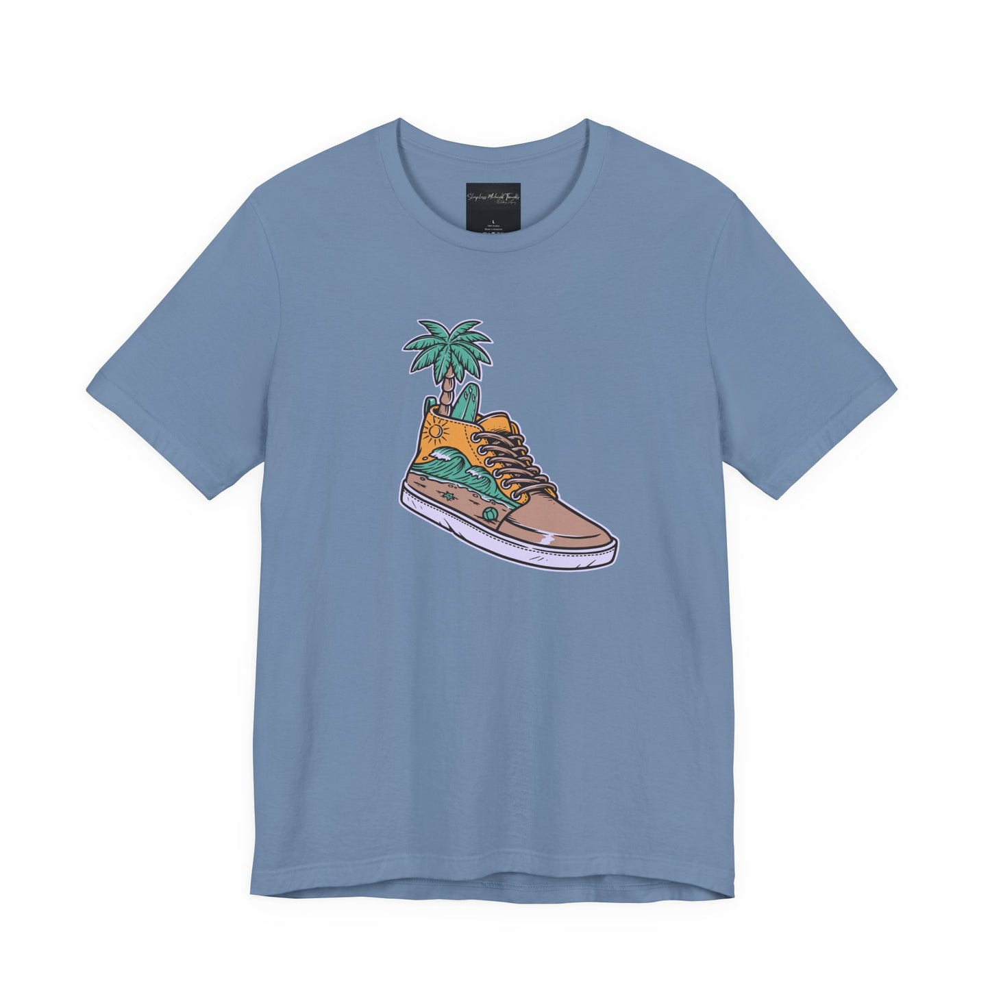 On the front of this custom handmade short sleeve shirt is an image of a high top running shoe with ocean waves running along the side of the shoe, coming out of the top of the shoe where your foot goes is a palm tree and a surf board.