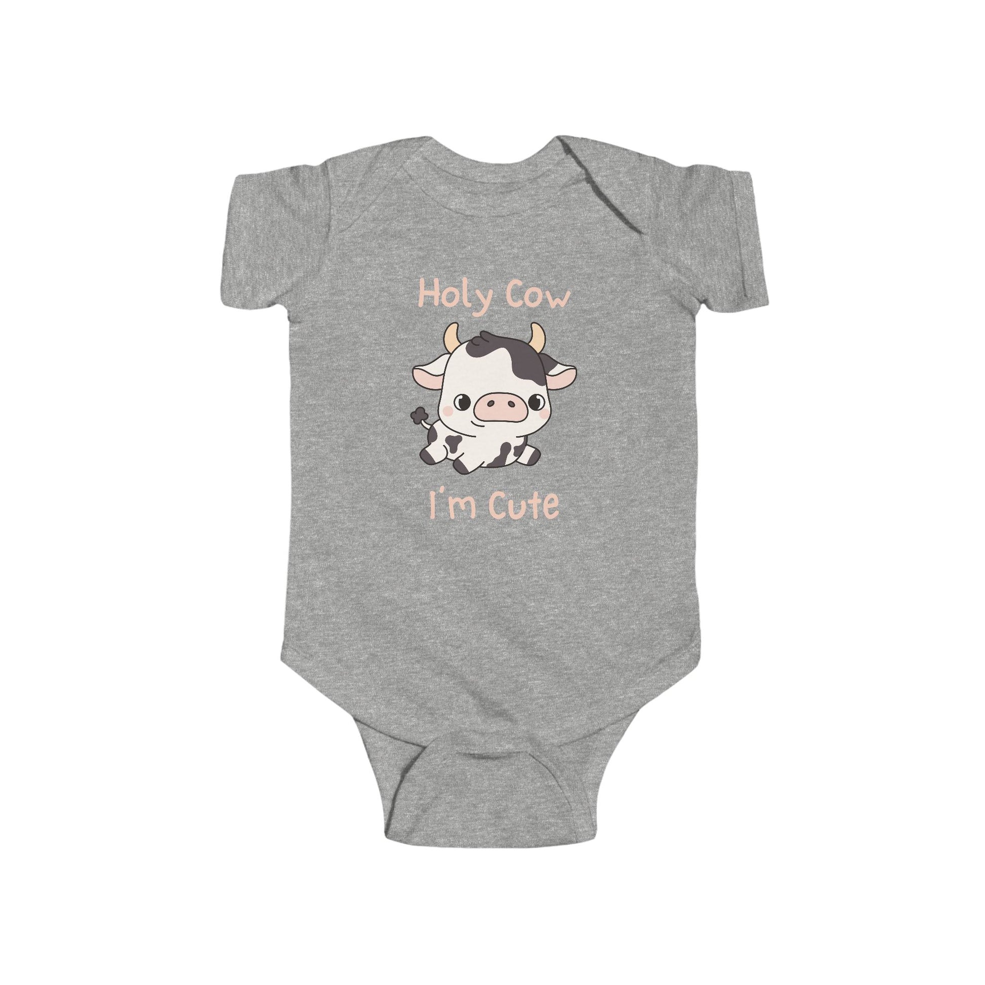 This adorable pink colored super soft bodysuit features an image of a baby cow in the middle with the words 'holy cow I'm cute' in light beige lettering around the image.