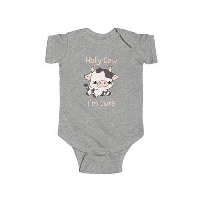 This adorable pink colored super soft bodysuit features an image of a baby cow in the middle with the words 'holy cow I'm cute' in light beige lettering around the image.