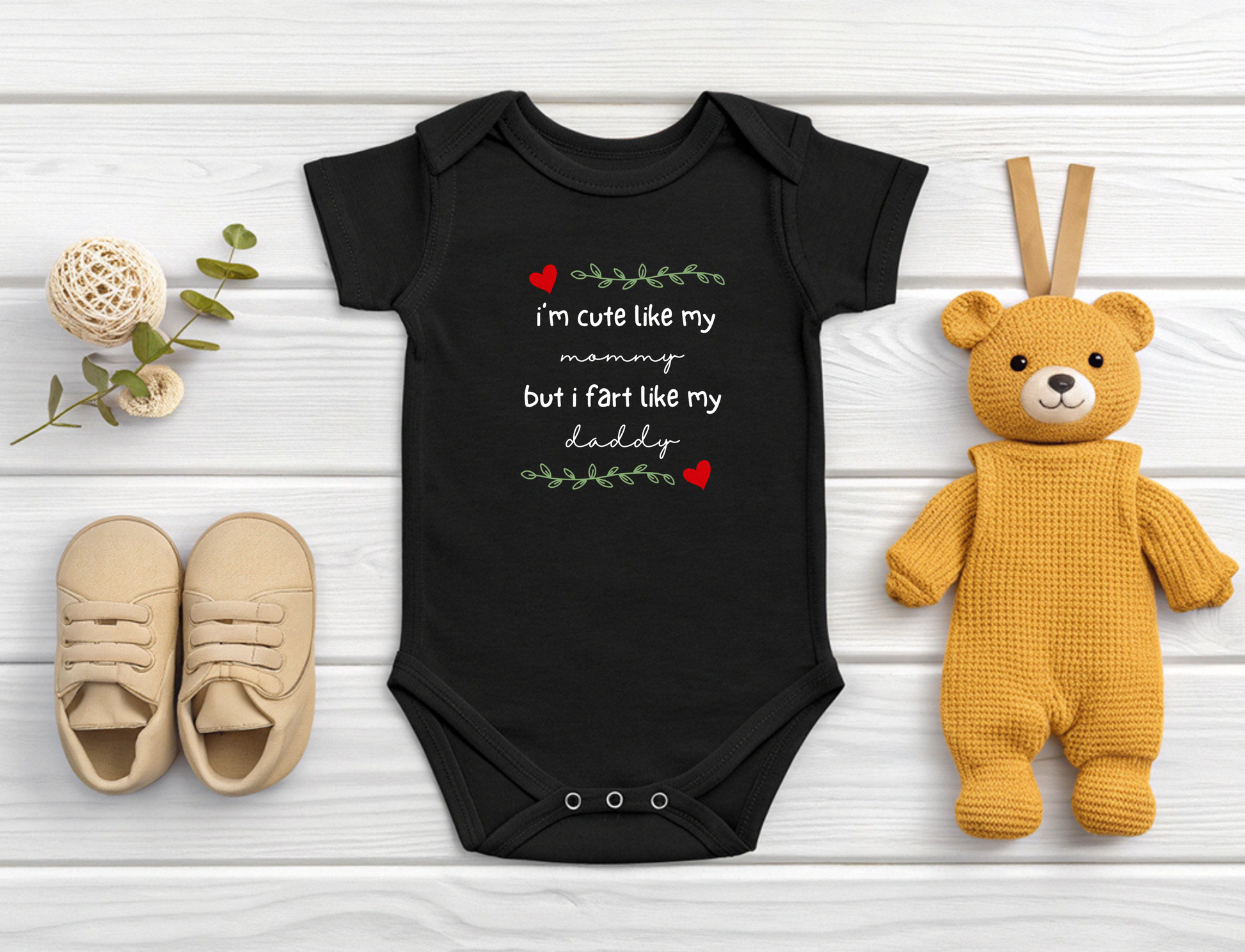 On the front of this custom short sleeve baby onesie are the words I'm cute like my mommy but I fart like my daddy with two hearts on either side of the writing.