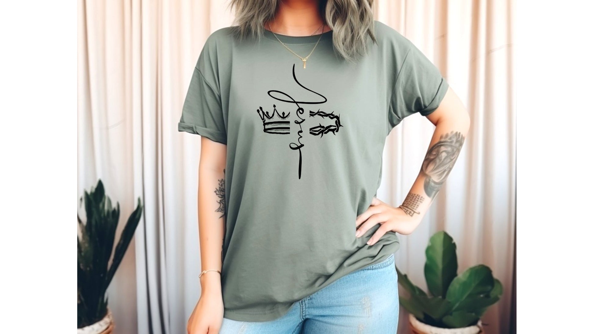 On the front of this custom Christian t-shirt is the name of Jesus in a cursive front from the top of the shirt facing towards the bottom, there is a crown on one side of the name and a crown of thorns on the other side of the name.