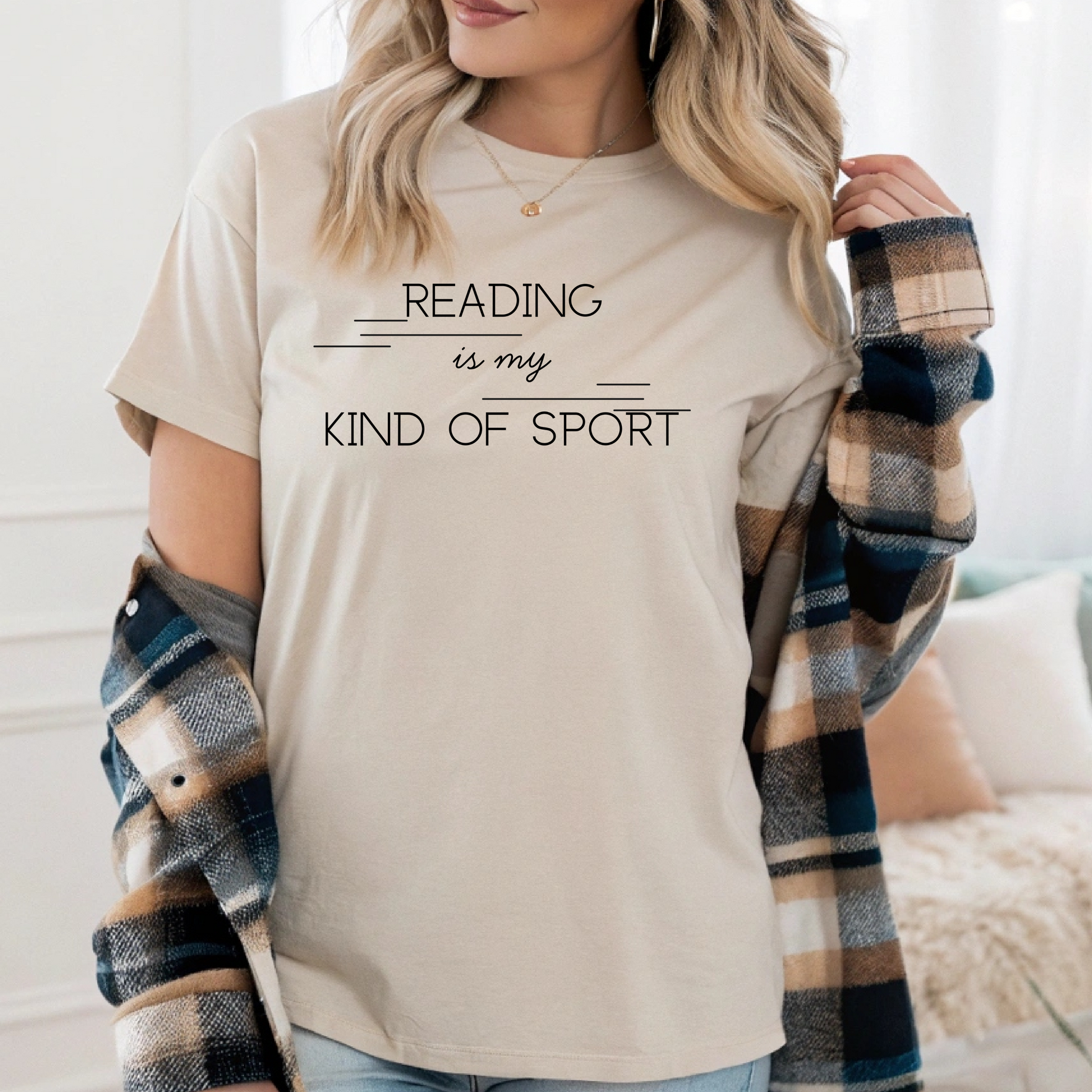 On the front of this custom booklover short sleeve shirt are the words Reading is my Kind of Sport, in a modern font with different length lines on either end of the writing giving the shirt a retro look.