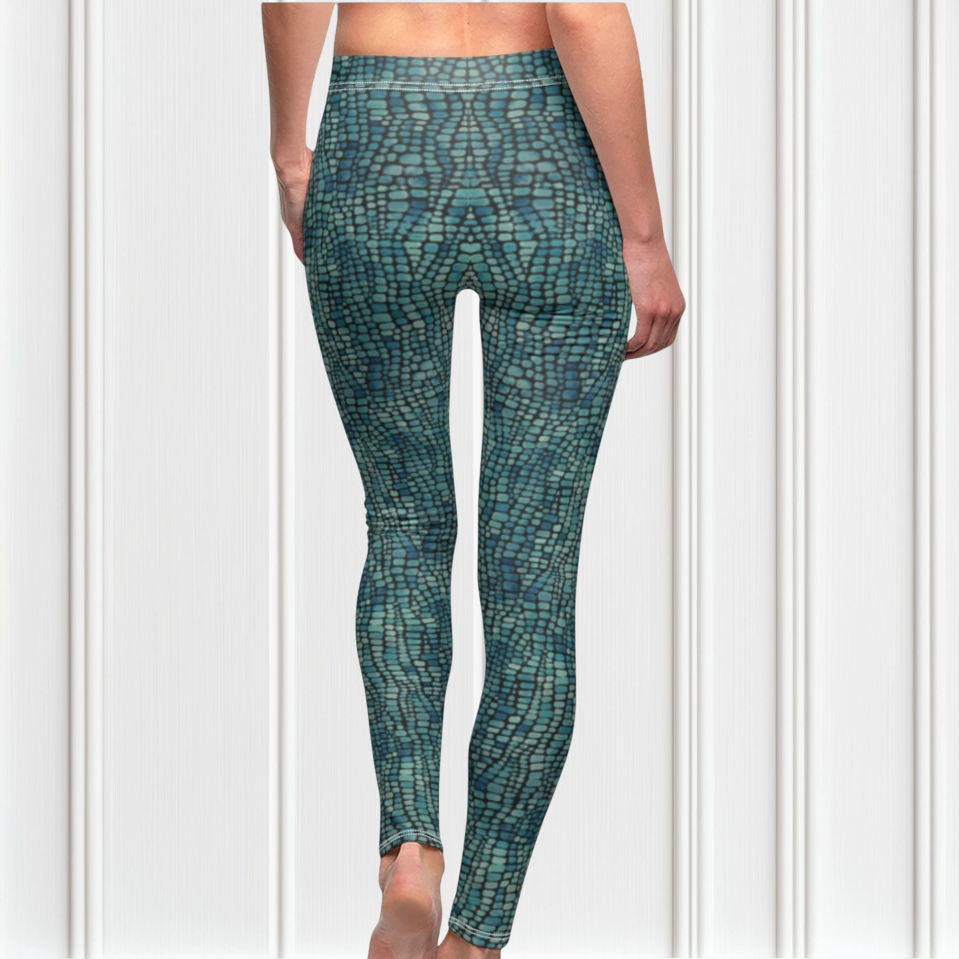 A pair of custom handmade high waisted women's leggings that have a emerald green and turquoise colored snake scale pattern all over the pants.