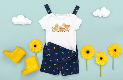 On the front upper part of this custom infant short sleeve onesie is an image of three baby chicks with flowers all around the baby chicks.