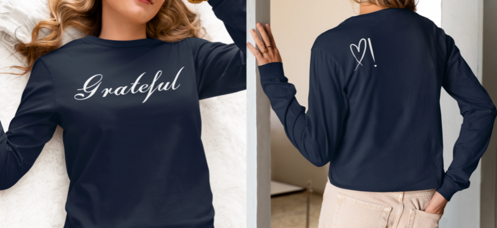 On the front of this custom long sleeve t-shirt in cursive writing is the word grateful on the upper chest, on the back left shoulder blade is an image of a heart with an exclamation mark next to it.