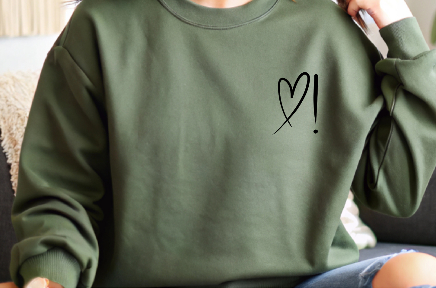 A handmade unisex oversized pullover sweatshirt with a crewneck, on the front left chest of the sweater in white is a heart with an exclamation point on the left hand side if the heart