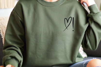 A handmade unisex oversized pullover sweatshirt with a crewneck, on the front left chest of the sweater in white is a heart with an exclamation point on the left hand side if the heart