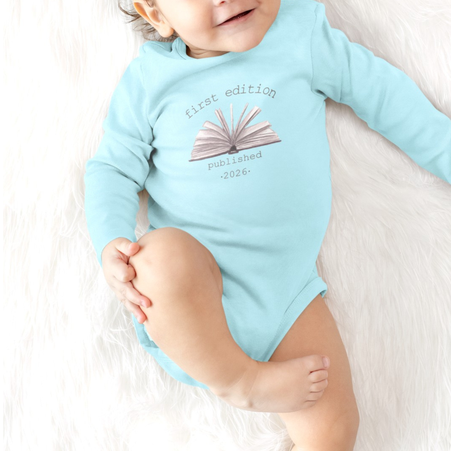 On the front of this custom baby onesie are the words First Edition Published 2026 with an image of an open book in the middle of the wording.