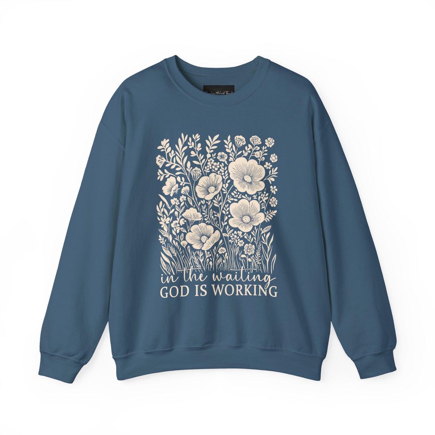 On the front of this custom women's Christian pullover sweatshirt are a bunch of wildflowers with the words in the waiting God is working underneath the flowers.