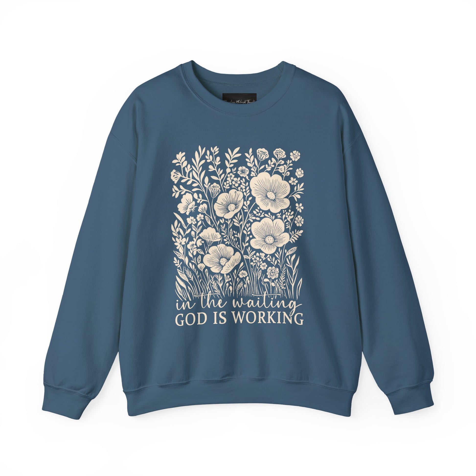 On the front of this custom women's Christian pullover sweatshirt are a bunch of wildflowers with the words in the waiting God is working underneath the flowers.