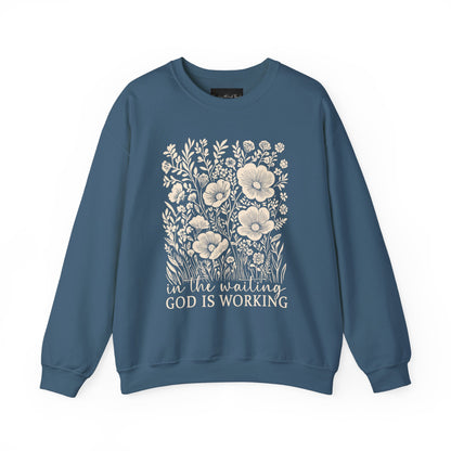 On the front of this custom women's Christian pullover sweatshirt are a bunch of wildflowers with the words in the waiting God is working underneath the flowers.
