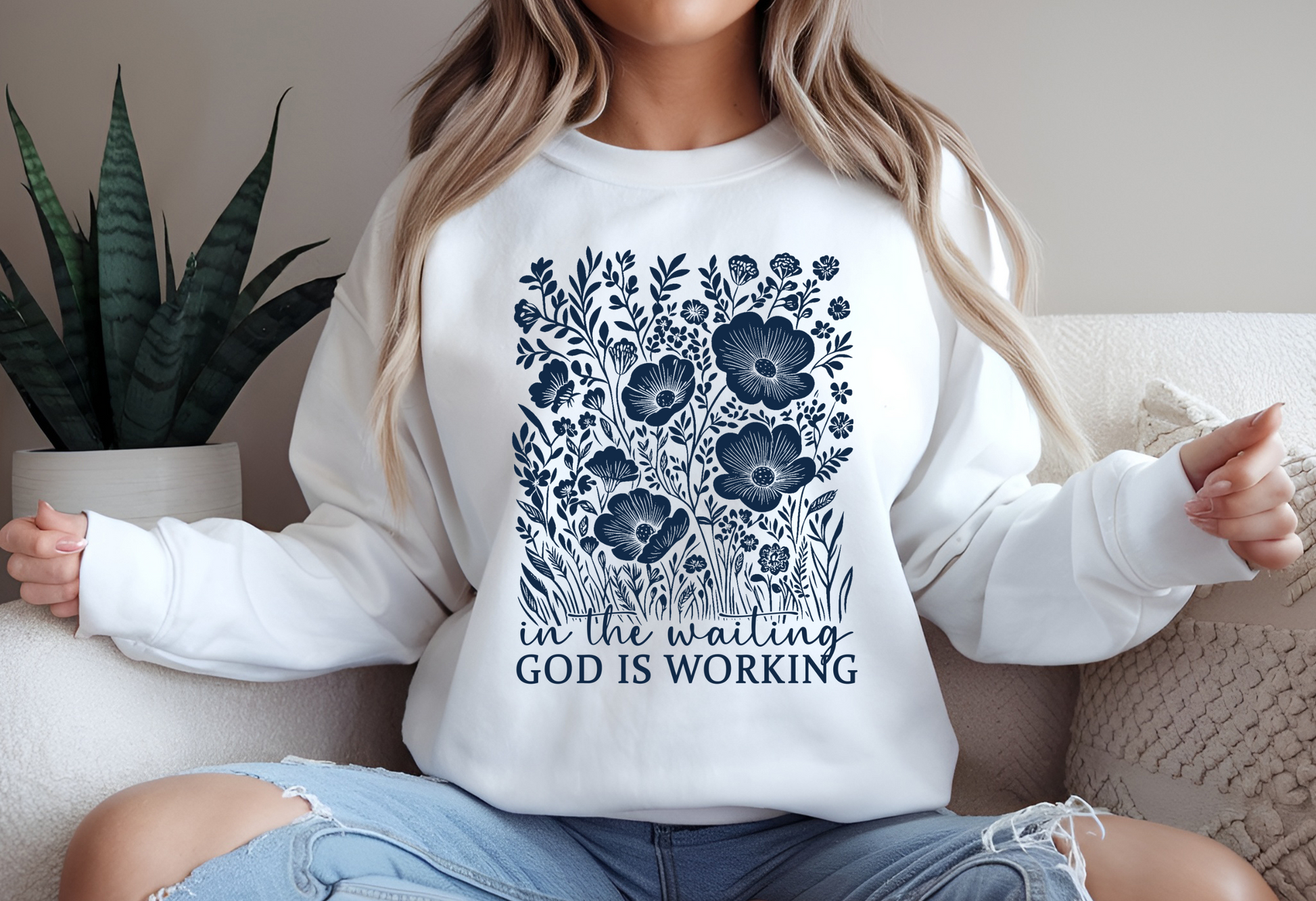 On the front of this custom women's Christian pullover sweatshirt are a bunch of wildflowers with the words in the waiting God is working underneath the flowers.