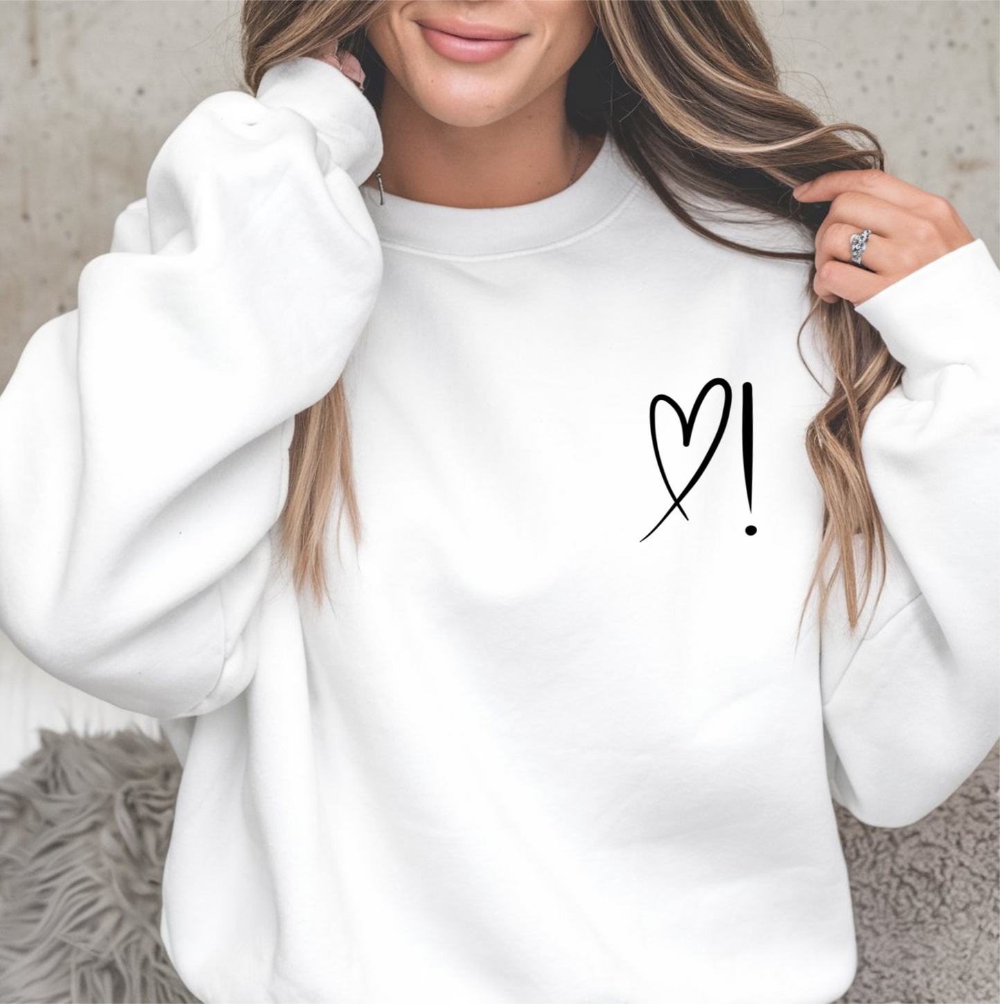 A handmade unisex oversized pullover sweatshirt with a crewneck, on the front left chest of the sweater in white is a heart with an exclamation point on the left hand side if the heart