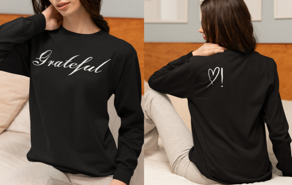 On the front of this custom long sleeve t-shirt in cursive writing is the word grateful on the upper chest, on the back left shoulder blade is an image of a heart with an exclamation mark next to it.