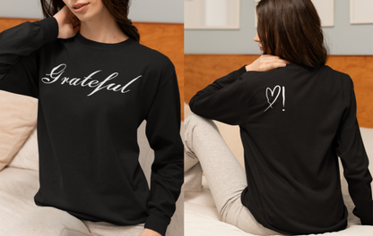 On the front of this custom long sleeve t-shirt in cursive writing is the word grateful on the upper chest, on the back left shoulder blade is an image of a heart with an exclamation mark next to it.