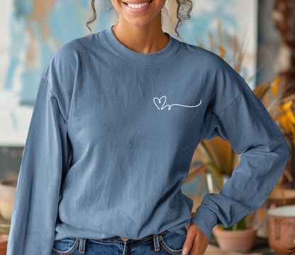 On the top right chest of this custom long sleeve t-shirt is a heart with a trail behind it signifying a heartbeat that you would see on a heart monitor. Perfect for health care workers and teachers.