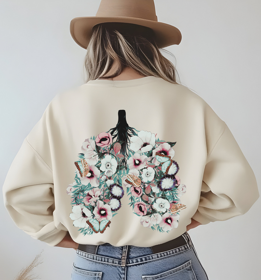 On the back of this women's pullover sweatshirt is an image of a set of lungs, but the lungs are made out of vines with pink and white flowers all over them, there are butterflies sitting in top of the flowers that are light blue in color.