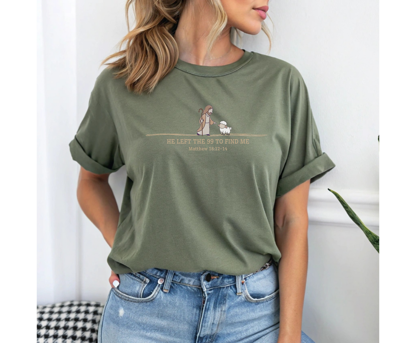 On the front of this custom Christian t-shirt is an image of Jesus the shepherd standing next to a little lamb, underneath the image are the words He left the 99 to Rescue Me Matthew 18:12-14.