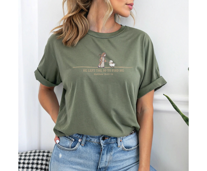 On the front of this custom Christian t-shirt is an image of Jesus the shepherd standing next to a little lamb, underneath the image are the words He left the 99 to Rescue Me Matthew 18:12-14.