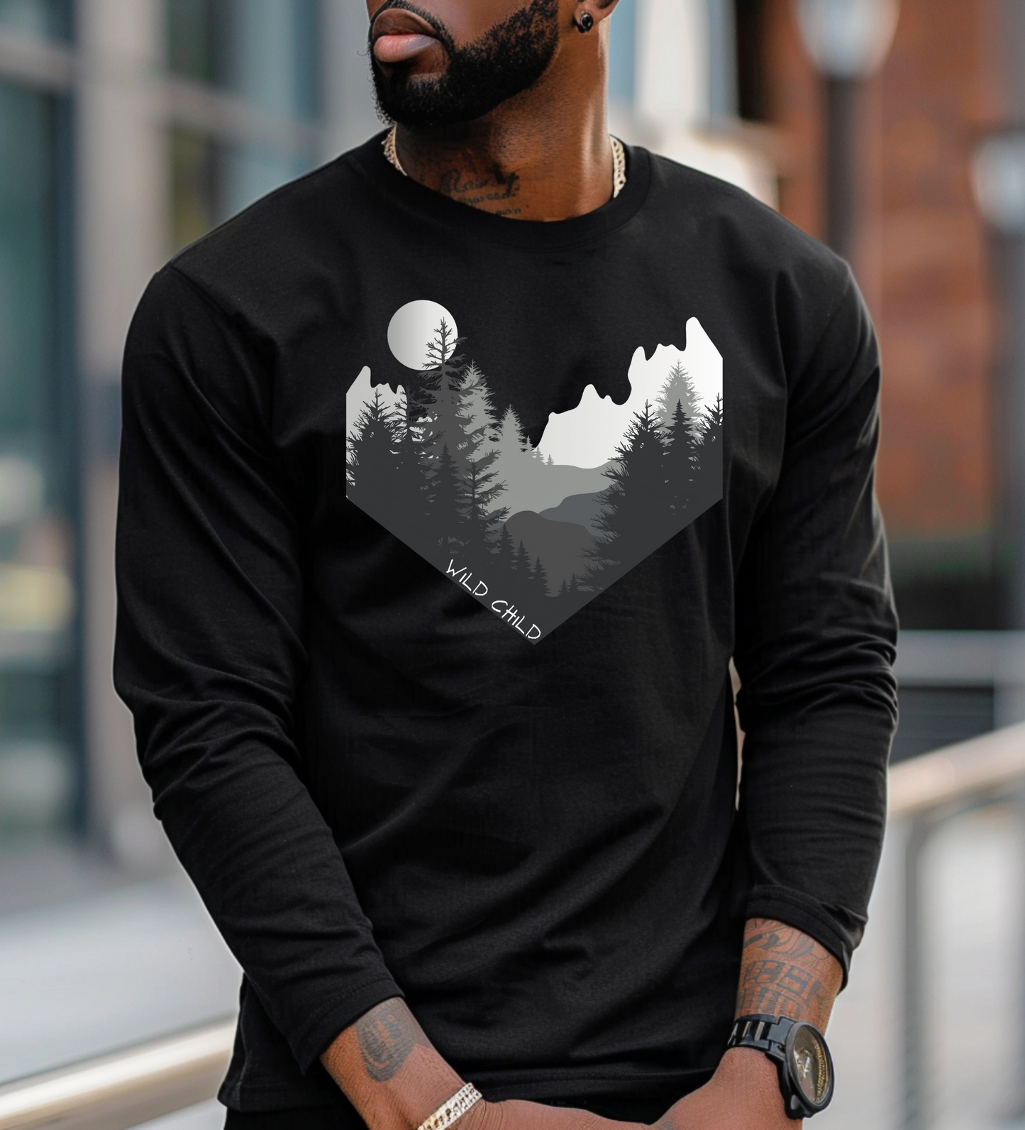 The image on the front of this custom long sleeve shirt is all in black and grey with there being mountains and trees on both sides in the shape on a v making it looking as if you are looking down a valley, the words wild child are in white on the bottom left of the image.