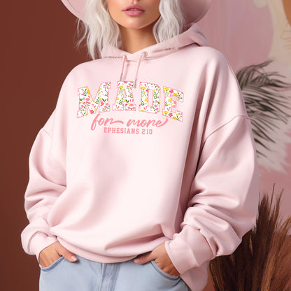 On the front of this custom Christian hoodie is the bible verse the says Made for more Ephesians 2:10, with the word "Made" being large block letters with a pink floral pattern inside the letters, all the other words are in a light pink color.