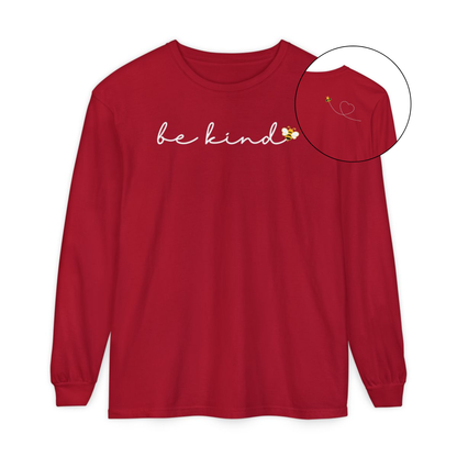 On the front of this custom unisex long sleeve shirt are the words be kind in a simple cursive font, with a bumble bee on the right side of the letter kind, on the back right shoulder there is an image of a bumble bee flying and leaving a trail behind it in the shape of a heart.