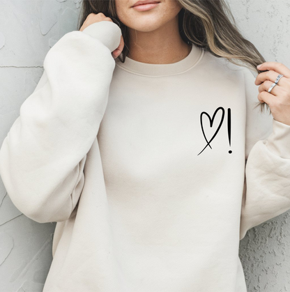 A handmade unisex oversized pullover sweatshirt with a crewneck, on the front left chest of the sweater in white is a heart with an exclamation point on the left hand side if the heart
