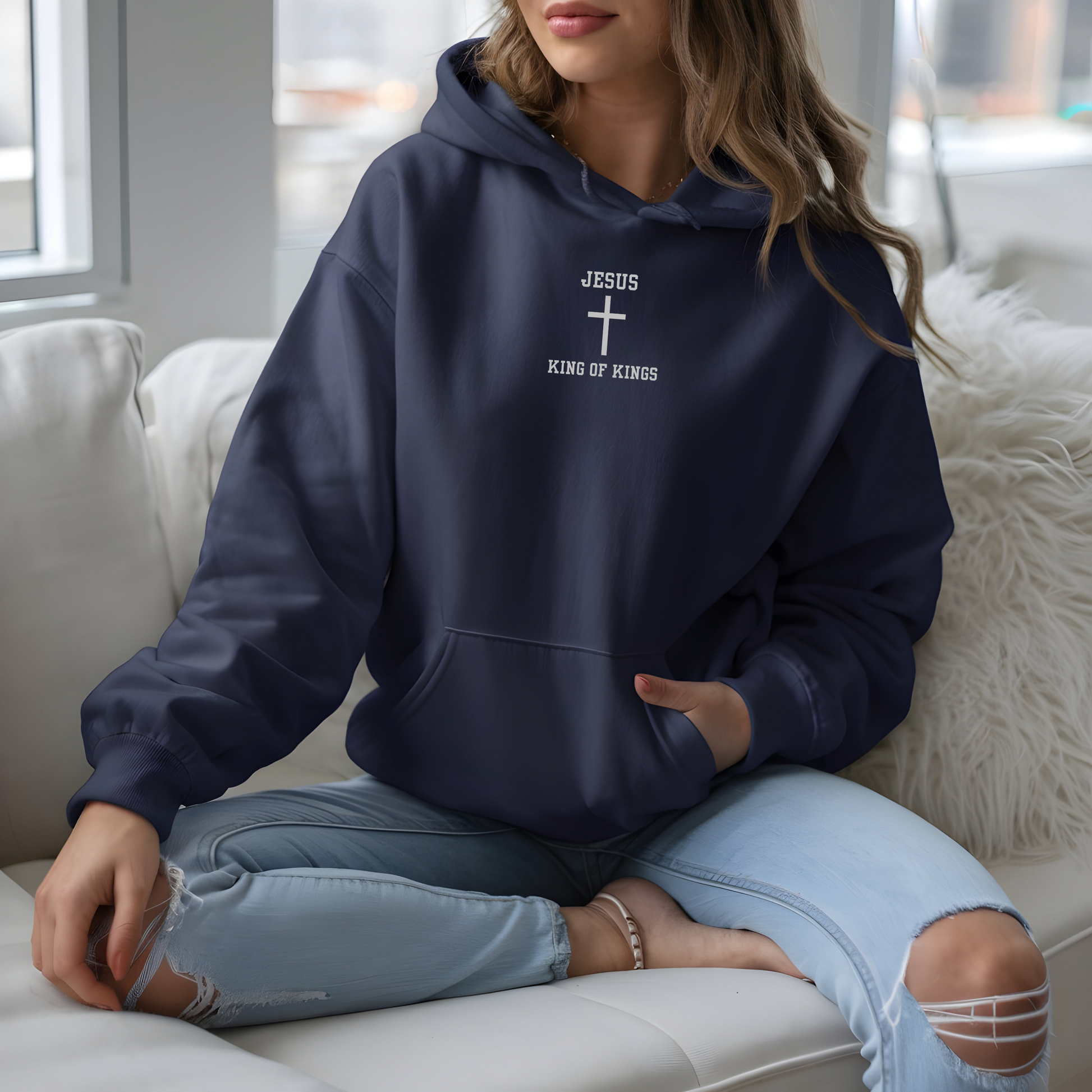 On the front of this custom embroidered unisex hooded sweatshirt are the words Jesus King of Kings with a Jesus cross in the center embroidered into the upper middle of the hoodie in silver thread.