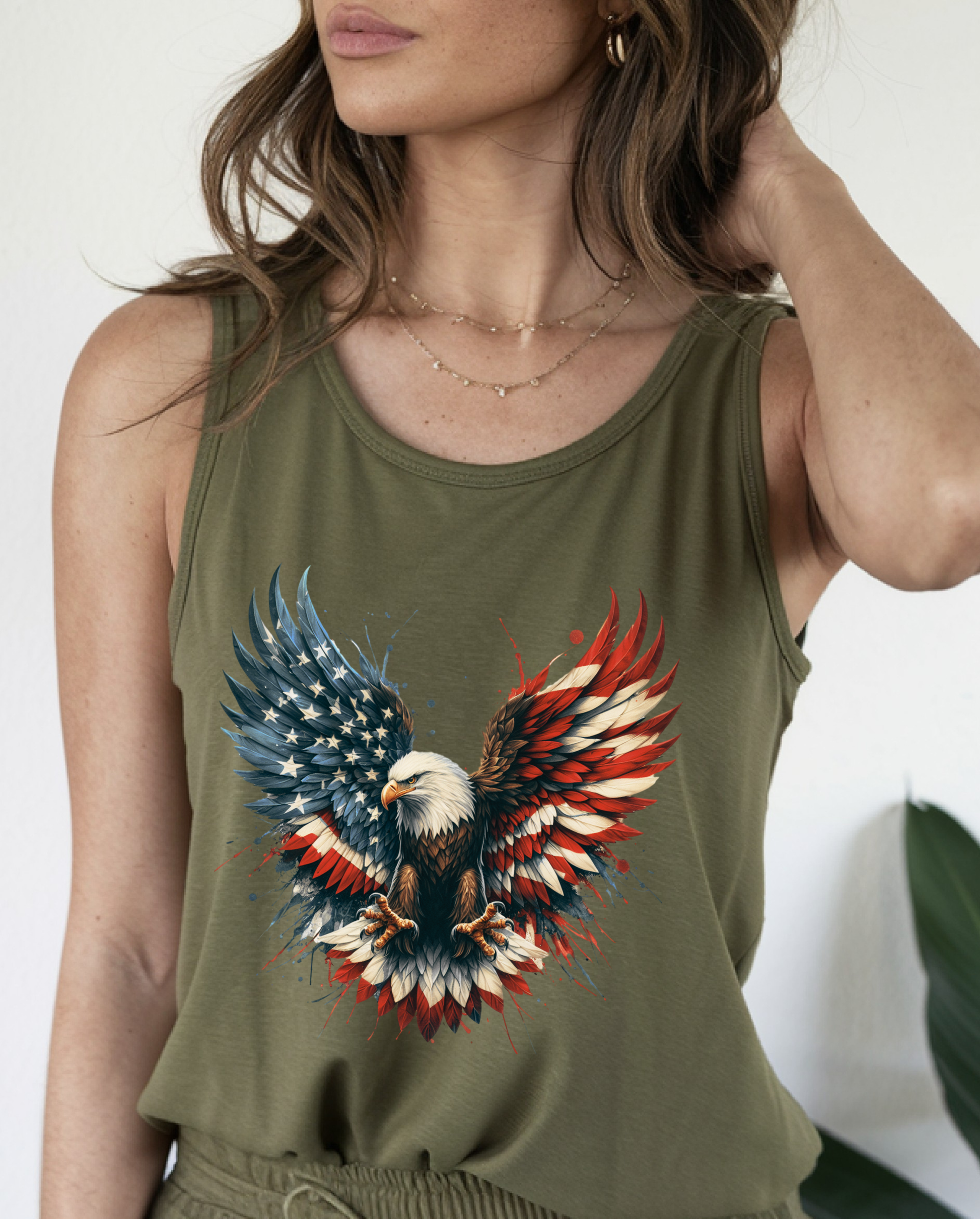 On the front of this unisex tank top is an image of an American Bald Eagle with it's wings out, the feathers of the bald eagle are the colors of the American flag being red, white and blue, there are also stars on one side of the eagle’s wings.