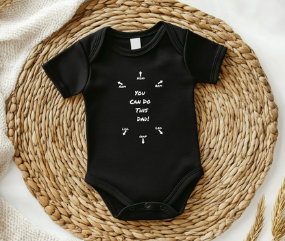 on the front of this custom infant onesie specifically meant for dads, are the words You can do this dad with arrows pointing where each leg and each arm goes along with were the babies head goes and where to close the snaps, a perfect diagram for a new father on how to put a onesie on a baby.