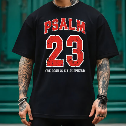 May include: Dark gray t-shirt with the text "PSALM 23" in red block letters above the number "23" in red. Below the number is the text "THE LORD IS MY SHEPHERD" in white. The shirt is a casual style.