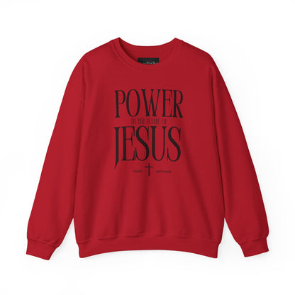 On the front of this Christian pullover sweatshirt it says Power In The Name Of Jesus with a Jesus cross underneath it, on either side of the cross are the words Fear and Nothing.