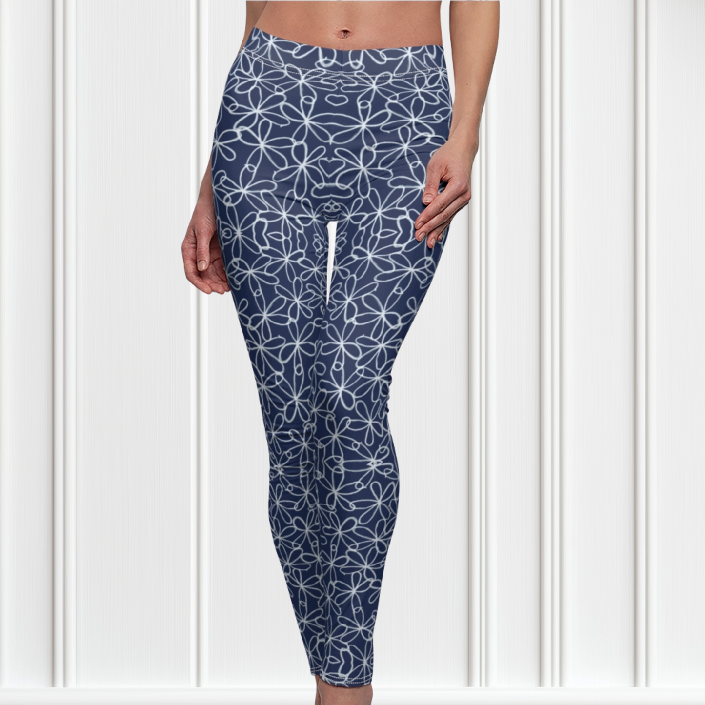A pair of navy blue women's high waisted leggings with a white floral pattern all over the handmade pants.