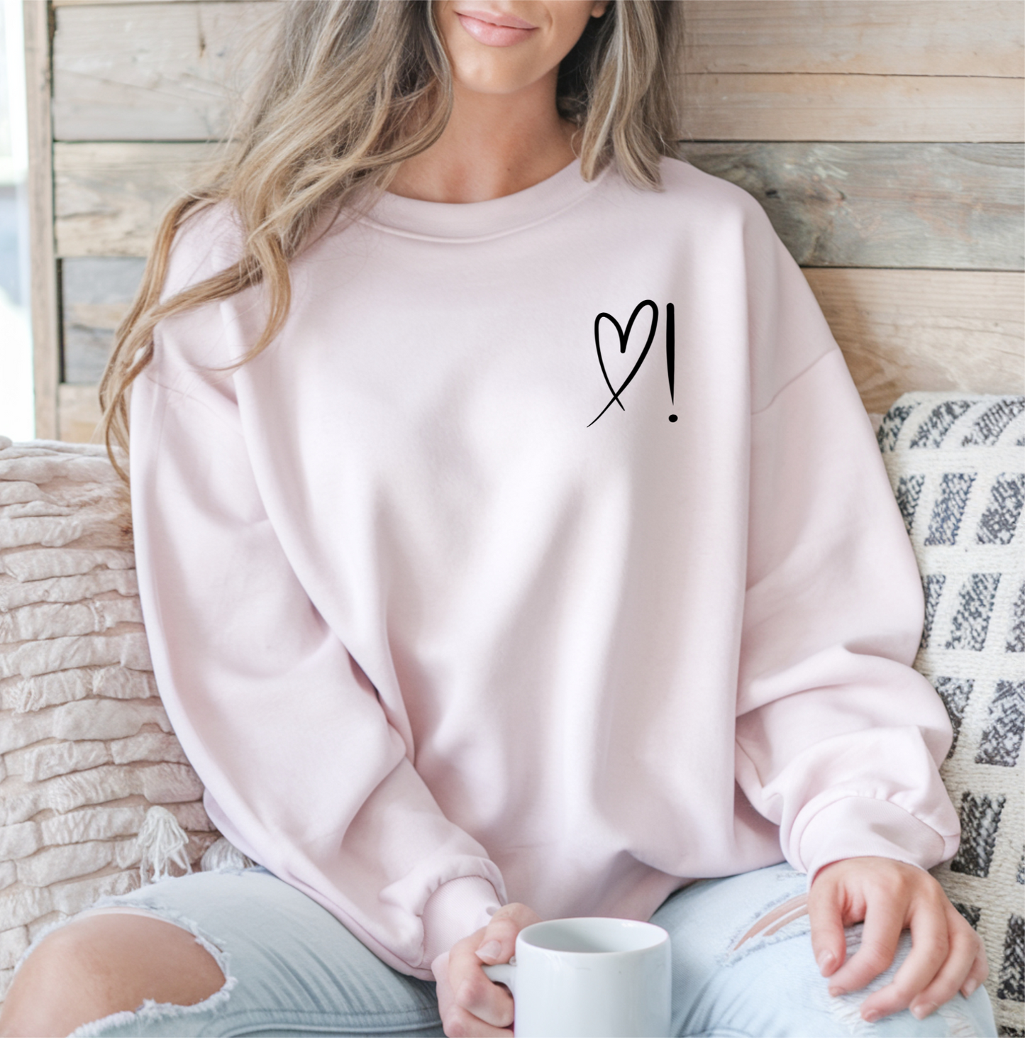 A handmade unisex oversized pullover sweatshirt with a crewneck, on the front left chest of the sweater in white is a heart with an exclamation point on the left hand side if the heart