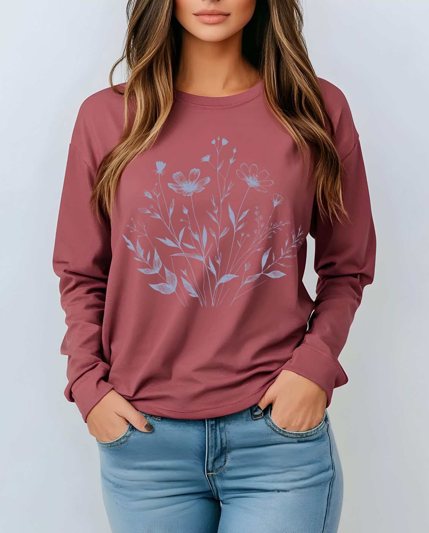 On the front of this custom women's long sleeve t-shirt is a image of a bunch of wildflowers and leaves coming from the bottom of the shirt to the very top, the flowers and leaves are in a light blue color.