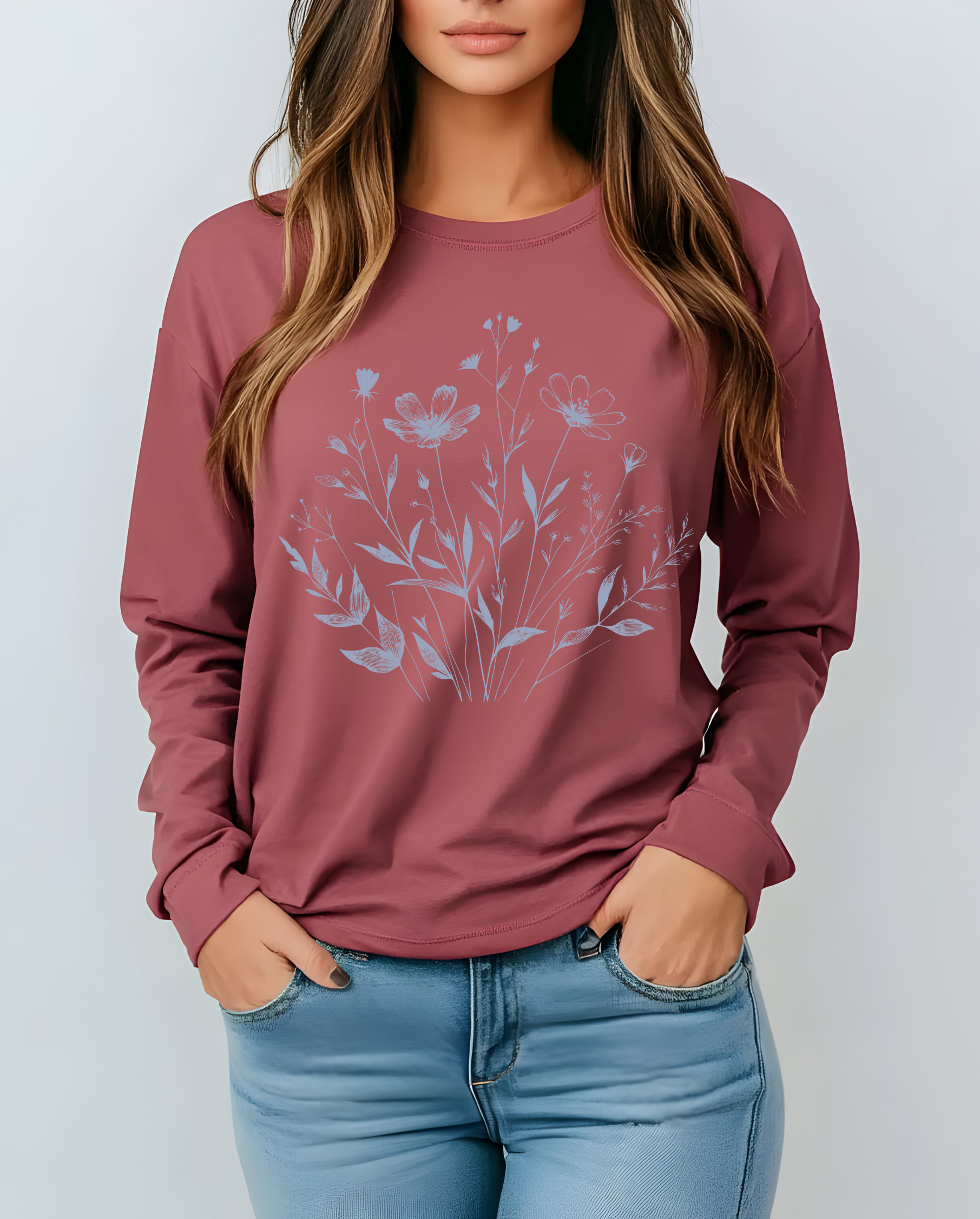 On the front of this custom women's long sleeve t-shirt is a image of a bunch of wildflowers and leaves coming from the bottom of the shirt to the very top, the flowers and leaves are in a light blue color.