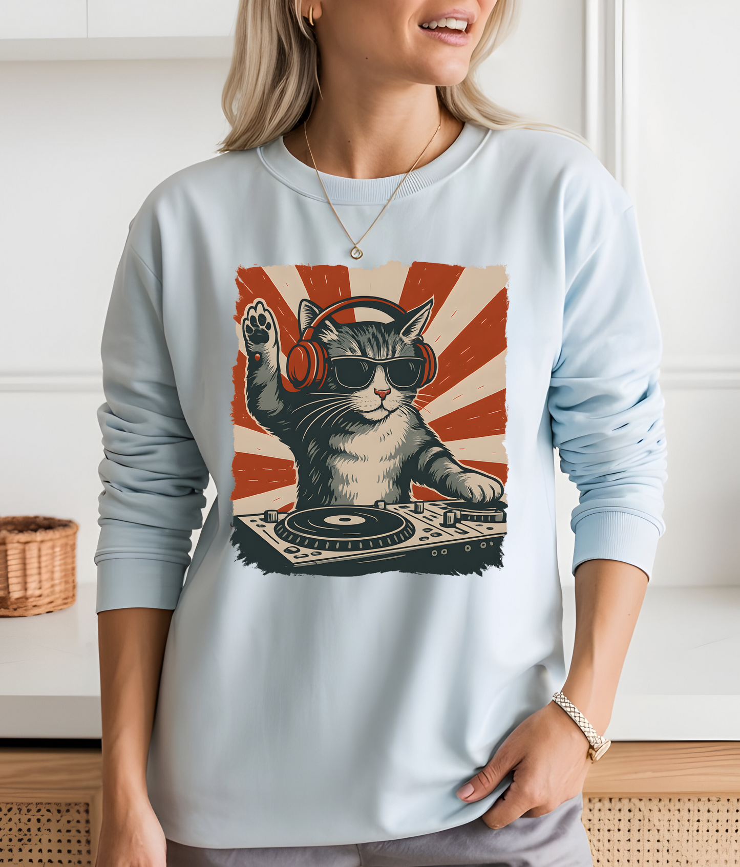 On the front of this custom retro long sleeve shirt is a DJ playing music, except the DJ is a cat that is wearing headphones, there is a vintage red and ivory background behind the cat.