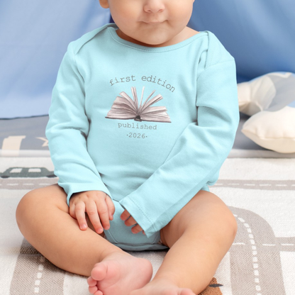 On the front of this custom baby onesie are the words First Edition Published 2026 with an image of an open book in the middle of the wording.