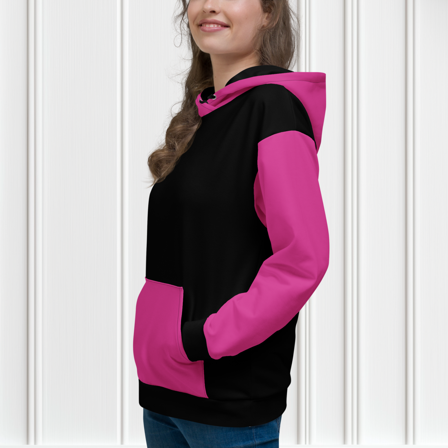 A women's custom oversized handmade hoodie, on the front and the back of the hoodie is the color black, the sleeves, front kangaroo pocket and hood are all a bright pink color, the strings of the sweater are black.