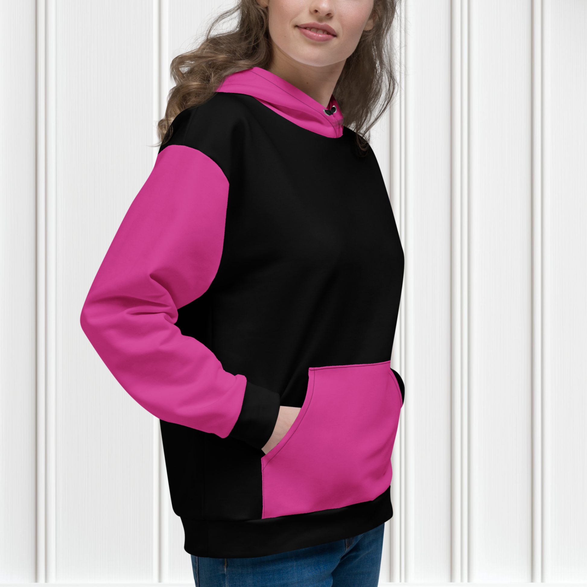 A women's custom oversized handmade hoodie, on the front and the back of the hoodie is the color black, the sleeves, front kangaroo pocket and hood are all a bright pink color, the strings of the sweater are black.