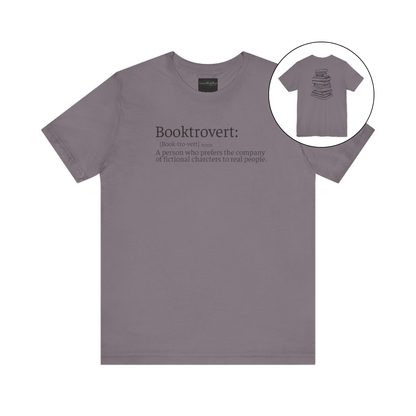 On the front of this custom unisex short sleeve shirt is the word booktrovert with the definition of the word underneath, on the back of the shirt is an image of a large stack of books.