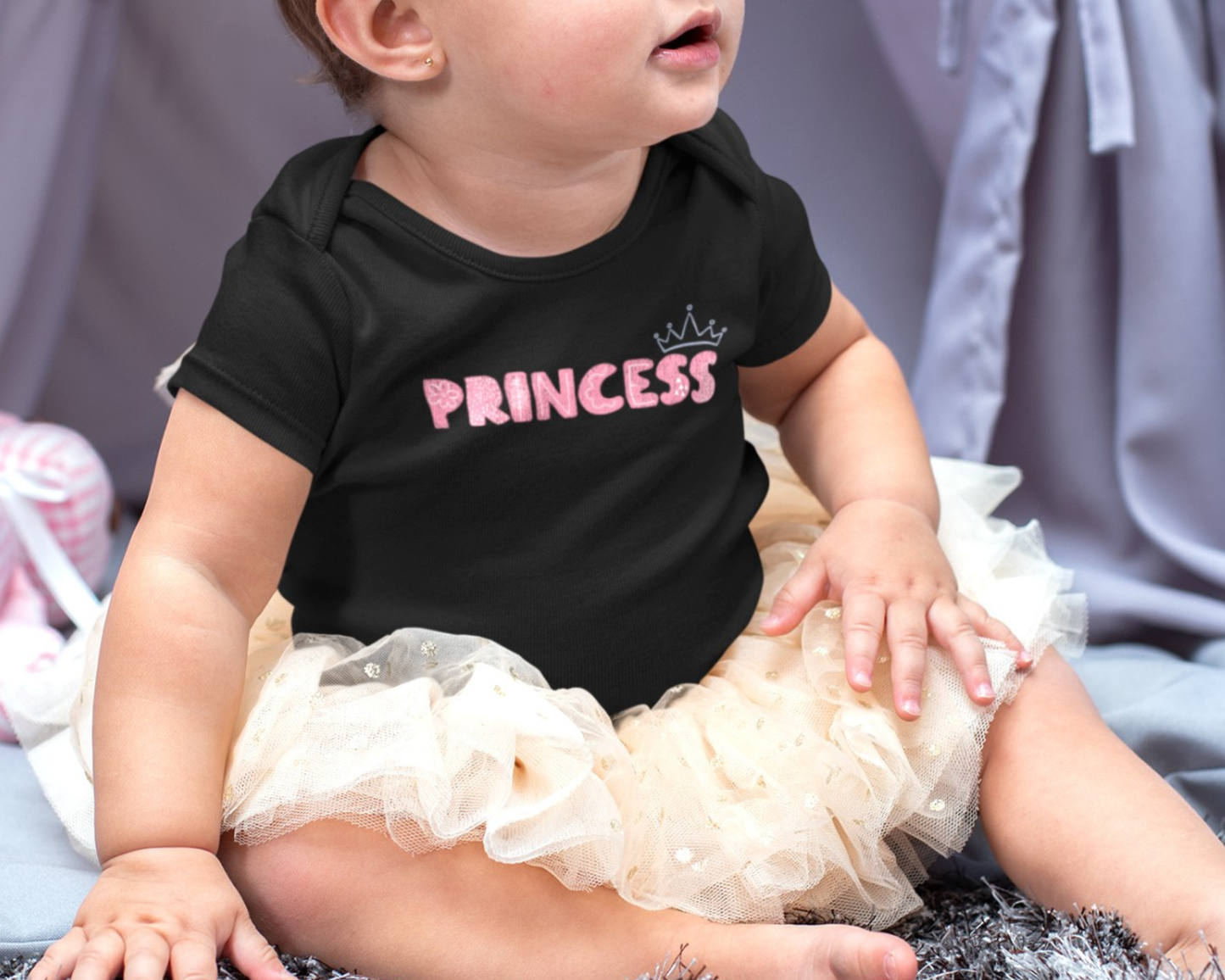 On the front of this custom baby girl onesie is the word princess in a light pink color with a crown over the last two letters of the word.