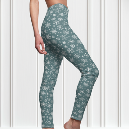 A pair of high waisted custom women's leggings that are a light blue in color and have white snowflakes all over the pants, perfect for Christmas.
