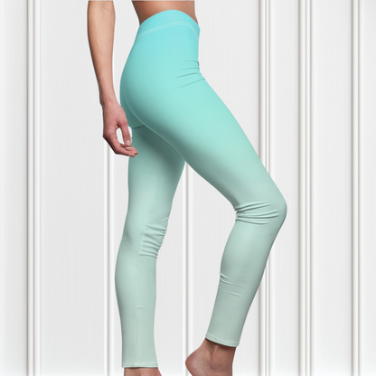 A pair of women's high waisted ankle length leggings that have a ombre pattern that starts as a medium ocean blue at the waistline then fades to a very light sky blue at the ankles of the pant.