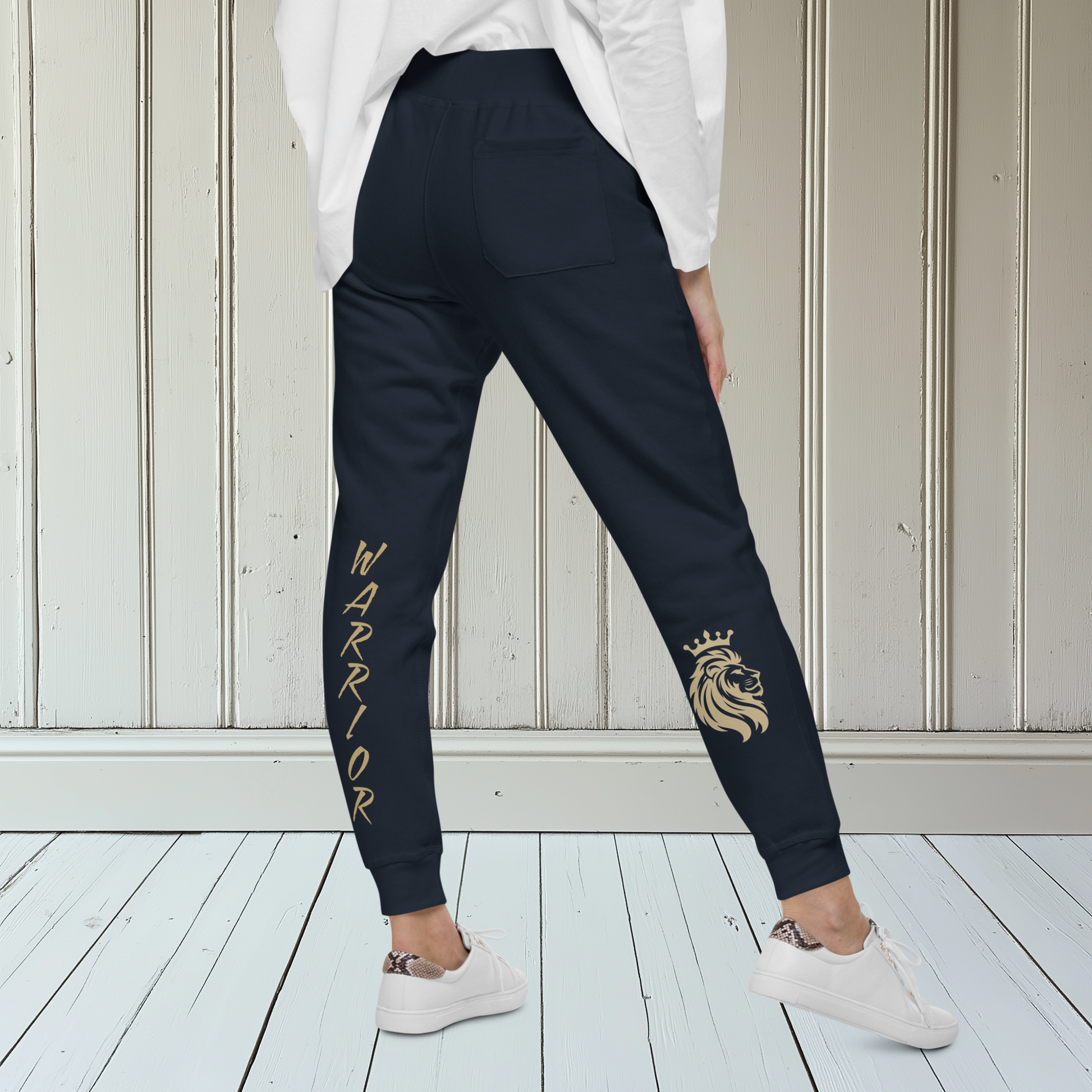 A pair of super soft ankle length unisex sweatpants, there are two pockets on the front and one pocket on the back right, the word warrior is in gold on the back left leg from the knee down and a male lion with a crown on the other