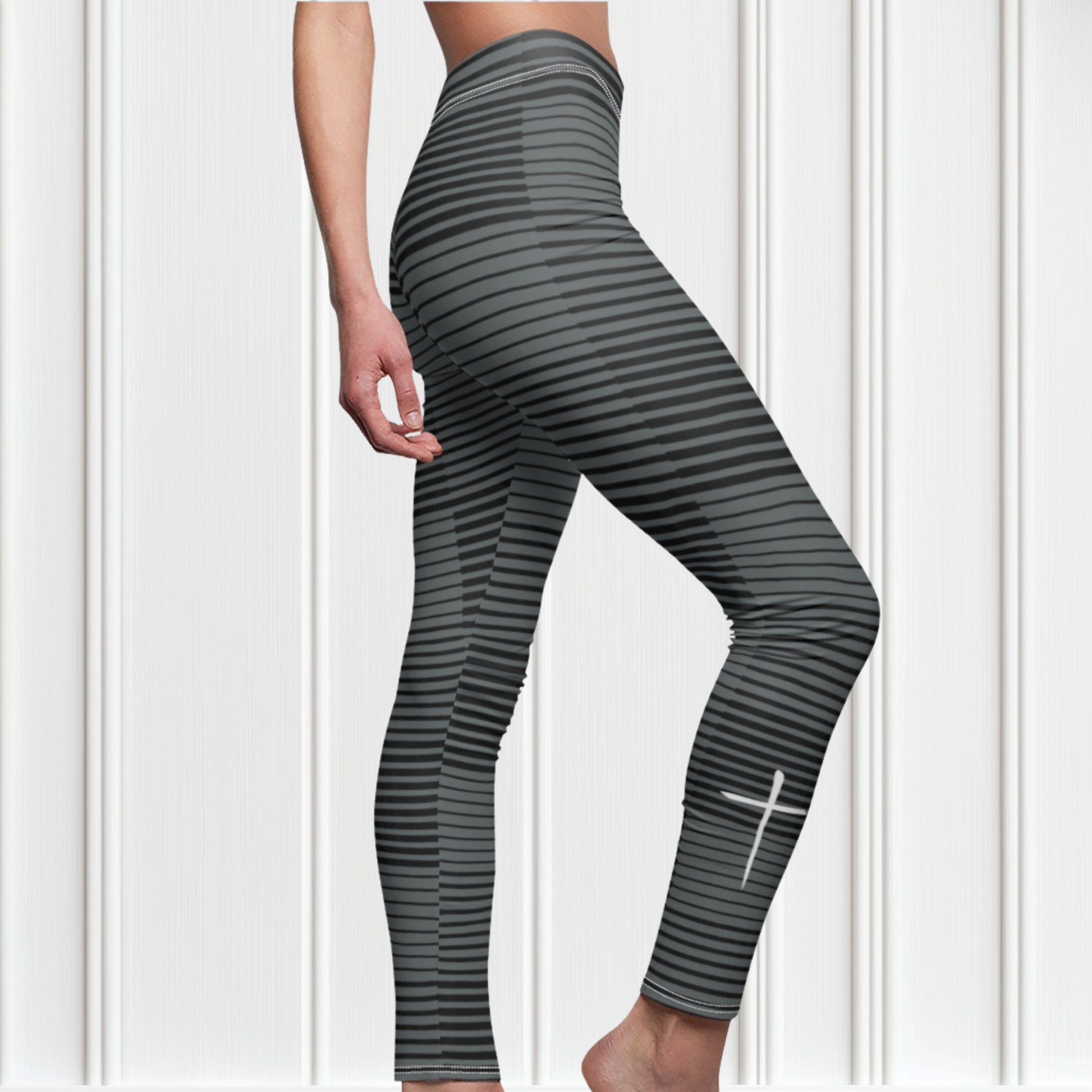 A pair of women's high waisted Christian themed leggings, the pants are light grey  color with black stripes running across the pants, the lines are in different thicknesses from the top to the bottom ankle of the leggings giving it a 3D look when worn, there is a white Jesus cross on the bottom right calf of the pant.